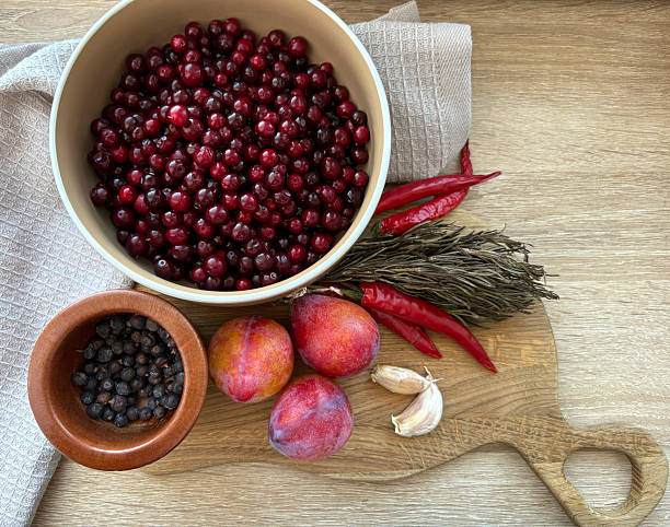 istock A kitchen table with produce, photo. A mortar with dried juniper berries, a bowl with red cranberries. Chili peppers, fresh rosemary, garlic. Garden plums, a towel on a wooden cutting board. Top view 2240190216