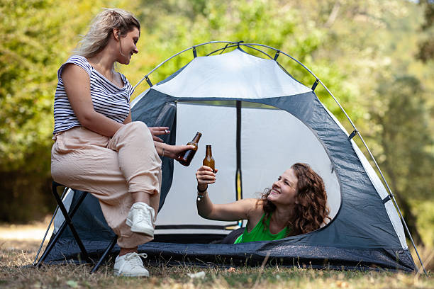 istock Two women are inside a tent, sharing drinks and laughter. The sun shines brightly through the trees, creating a warm outdoor atmosphere perfect for camping and relaxation among nature 2240196594