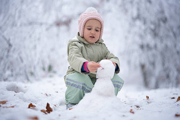 istock Child Making A Snowman. Winter Play in Snowy Forest 2240197981