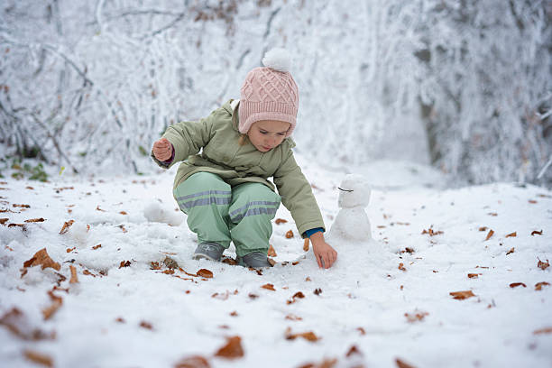 Child Making A Snowman. Winter Play in Snowy Forest