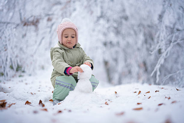 istock Child Making A Snowman. Winter Play in Snowy Forest 2240197989