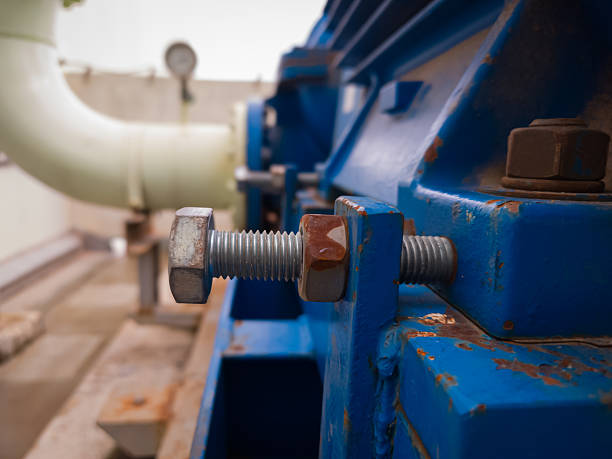 istock Close-up of a large bolt with dual nuts securing a motor base in an industrial setting. Rust and wear indicate active use in a mechanical system. 2240204554