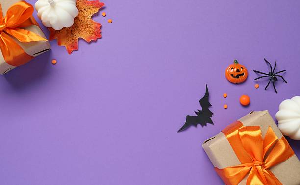 istock Halloween background with gift box, bats and pumpkins on purple background 2240204989