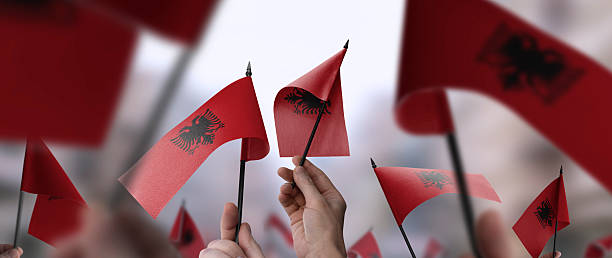 istock Albania flags in their hands on a blurred urban background 2240205963