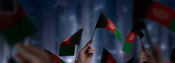 Afghanistan flags in their hands on a blurred urban background. The photo illustration was created without the use of artificial intelligence, only using Photoshop.