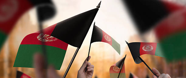 istock Afghanistan flags in their hands on a blurred urban background 2240206077