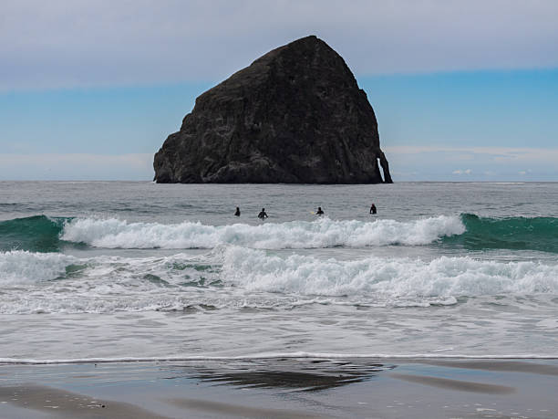 istock Waves Four Surfers And Haystack Rock Cape Kiwanda Oregon 2240208124