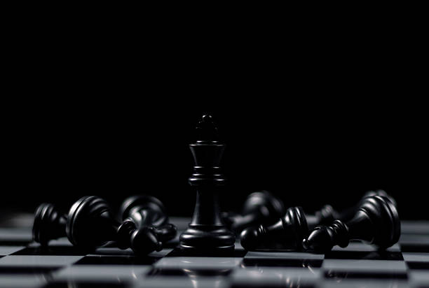 Queen chess piece stands among fallen silver knights, rooks, bishops and pawns on a chessboard. Leadership, winner, competition, business strategy concept. Game of strategic power, planning.