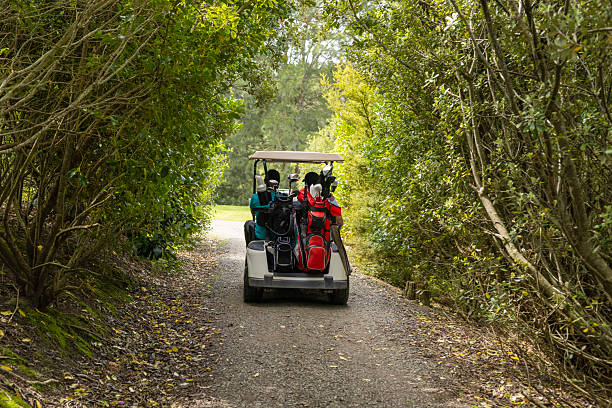 Asian man driving a golf cart on a golf course