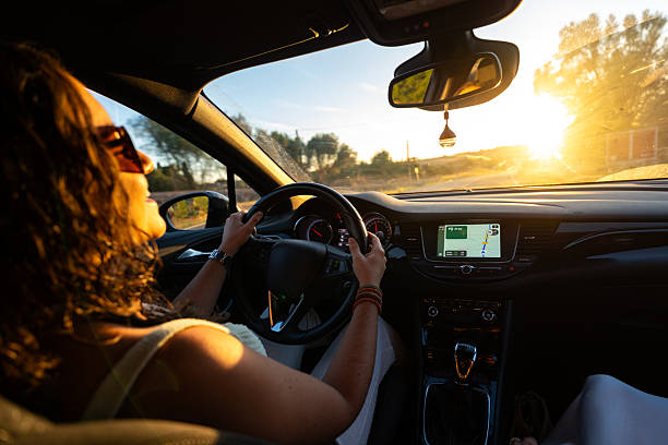 Woman driving car on a sunny road, navigating with gps during a golden hour journey
