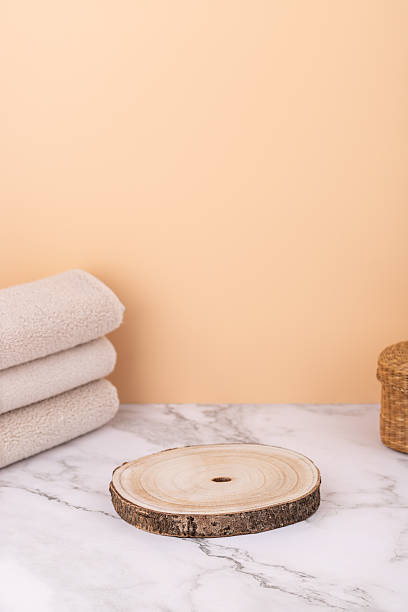 istock Vertical composition with rustic wooden base, folded beige towels and wicker basket on marble table with peach background. Minimalistic style with copy space. Concept of spa decoration and cozy lifestyle 2240212611