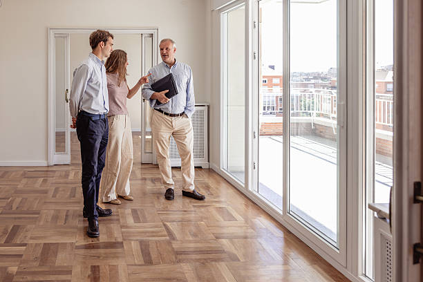 istock Real estate agent talking with young couple inside new empty apartment 2240215509