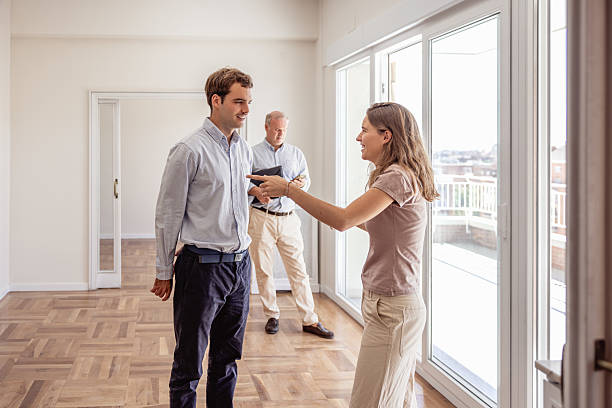 istock Young couple discussing empty apartment with real estate agent in the background 2240215529