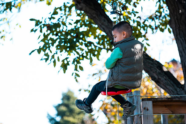 istock Boy playing on fall zipline swing in park 2240220508