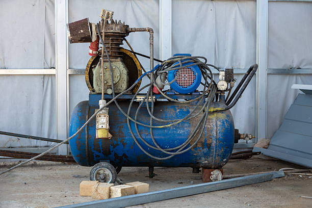 An old blue Working mobile air compressor for painting walls on a construction site. Engineering equipment.