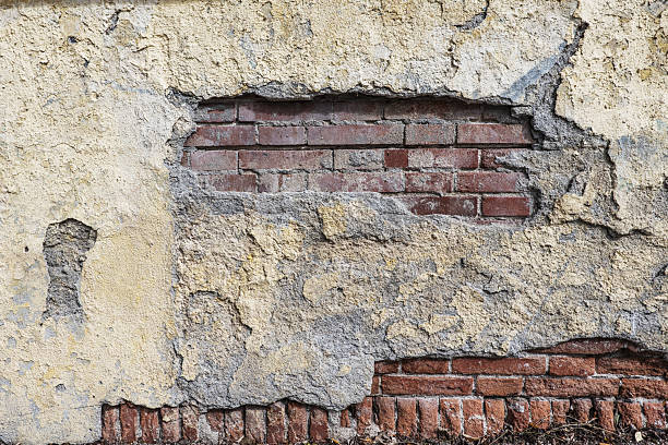 istock Old clay brick wall covered in cement and paint with large chipped pieces 2240222364