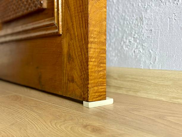 istock Improvised door stopper using a white rubber eraser under an old wooden door on a laminate floor 2240224848