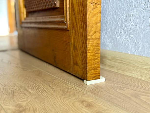 istock Improvised door stopper using a white rubber eraser under an old wooden door on a laminate floor 2240224904