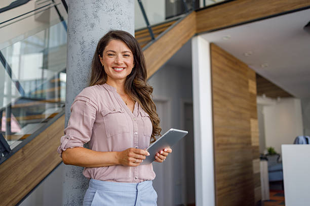 istock Businesswoman holding digital tablet smiling in modern office 2240225017