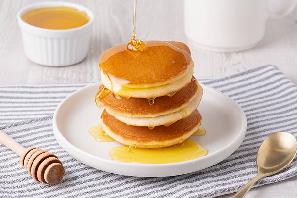 Delicious fluffy pancakes with syrup served on a white plate for breakfast