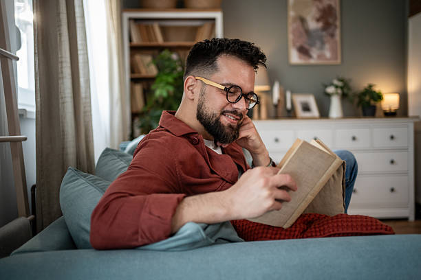 istock Man relaxing on sofa reading book at home 2240226449