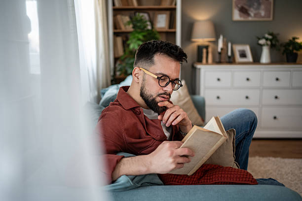 istock Young man relaxing at home reading a book 2240226490