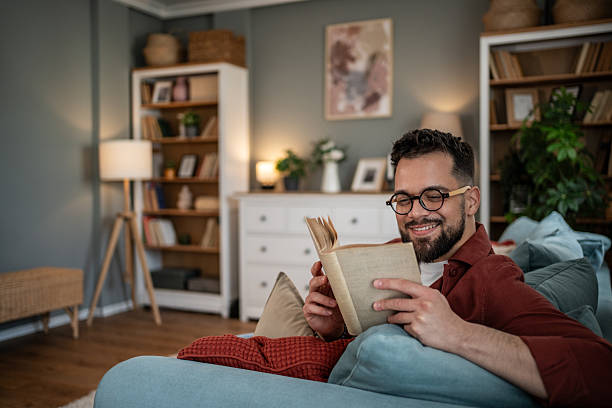 istock Man relaxing at home reading book in living room 2240226510