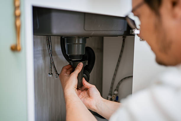 istock Skilled plumber installing siphon under kitchen sink, carefully connecting pipes and checking connections to prevent water leakage and ensure proper drainage system functionality 2240229316