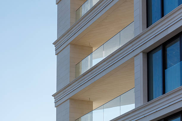 A building with a balcony on the top floor. The balcony is made of glass. The building is tall and has a lot of windows