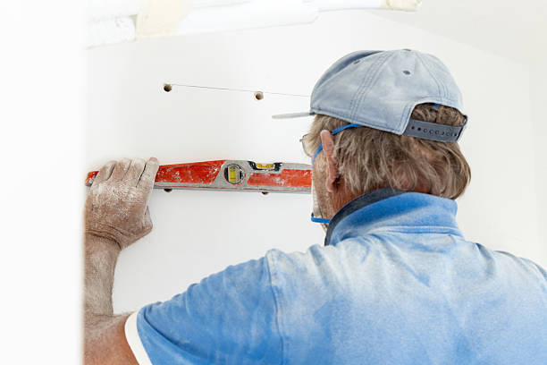 istock Senior craftsman levelling surface during drilling a wall, closeup. DIY home improvement 2240233592