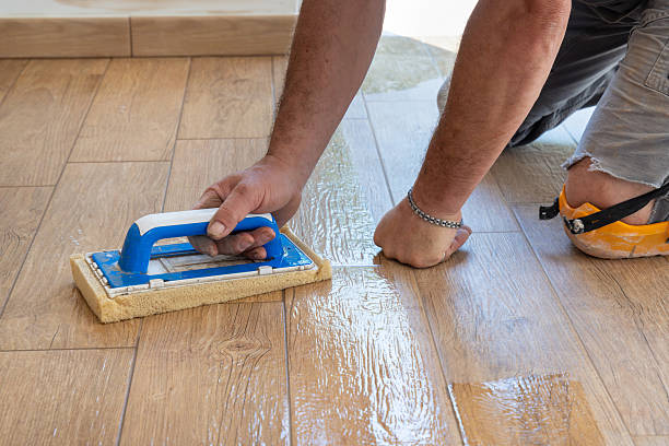 istock Craftsman washing tiled floor with a sponge float during construction of a building, hand closeup 2240233596