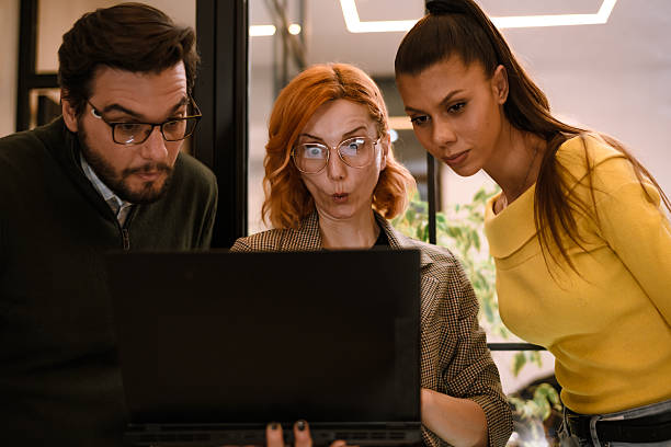 istock Three coworkers in a modern office concentrate on a laptop screen while engaging in an interesting discussion about a project at work 2240234189