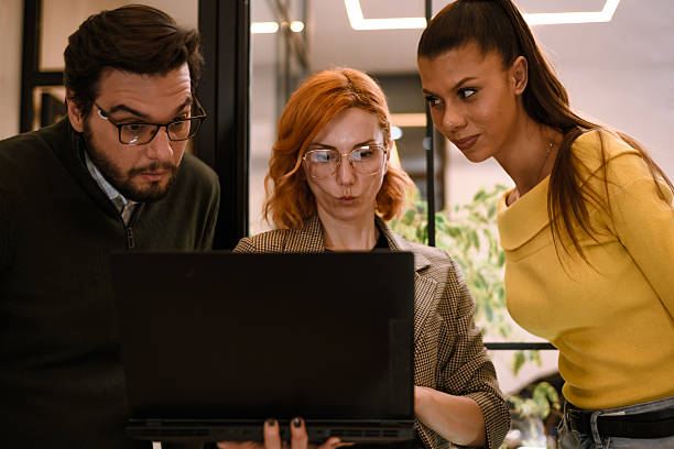 Team collaborates on laptop in modern office setting during afternoon work session