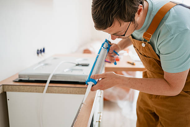 istock Professional handyman applying silicone sealant around kitchen countertop edges, using caulking gun for waterproof sealing and smooth renovation work 2240237642