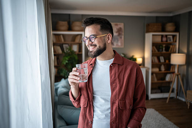 istock Young man smiling and drinking water at home 2240238171