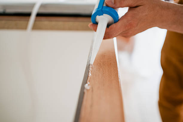 istock Construction worker sealing wooden plank with silicone using caulking gun, creating waterproof barrier during home repair and renovation project 2240238577