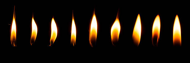istock Row of glowing candle flames on black background 2240239275