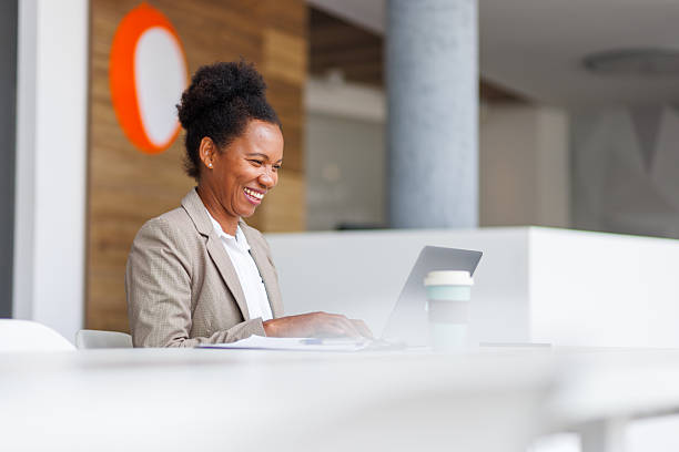 istock Black businesswoman smiling, laughing while working on laptop in office 2240242867