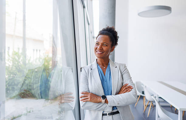 istock Confident businesswoman smiling and looking through office window 2240242978