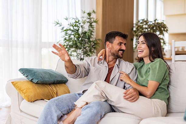 istock Happy couple relaxing at home laughing on sofa 2240245746