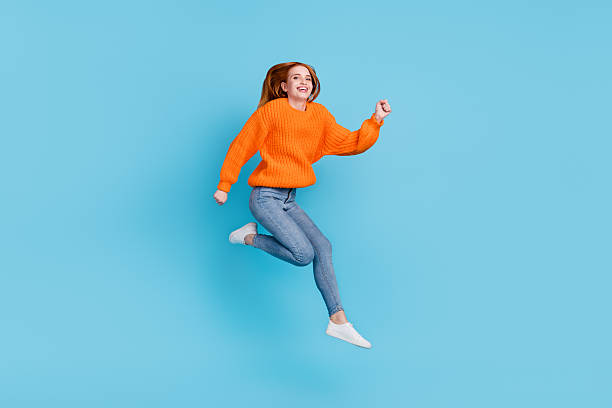 istock Photo of pretty charming young lady dressed oversize pullover smiling jumping high isolated blue color background 2240246491