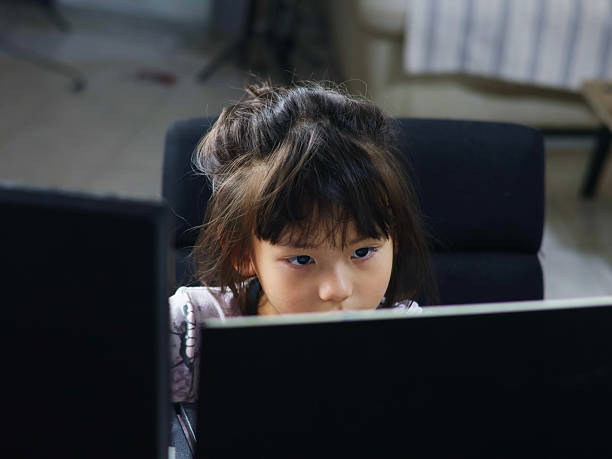 istock Image of a young girl staring at a computer screen with a serious gaze. 2240247424