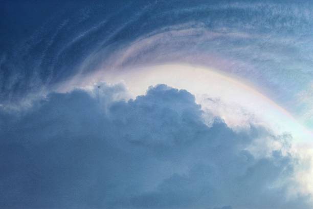 istock a sky with dramatic blue and white cloud formations, accompanied by a faint rainbow of light in the form of an arch above the clouds 2240248221