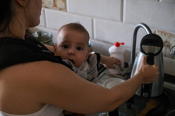 istock Mother cooking with baby in carrier 2240252357