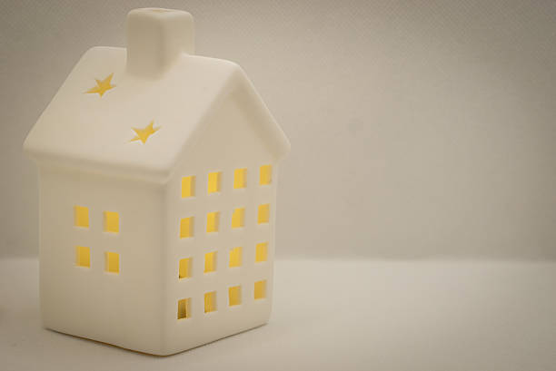 White ceramic toy cosy house lightning inside with tiny windows in the white background