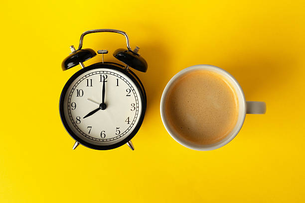 istock Alarm clock and coffee cup on yellow background, top view 2240253646