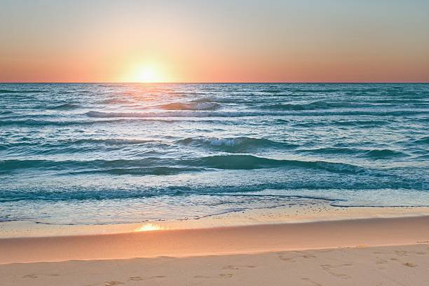istock Colorful sunset viewed from the sea beach with soft waves 2240255790