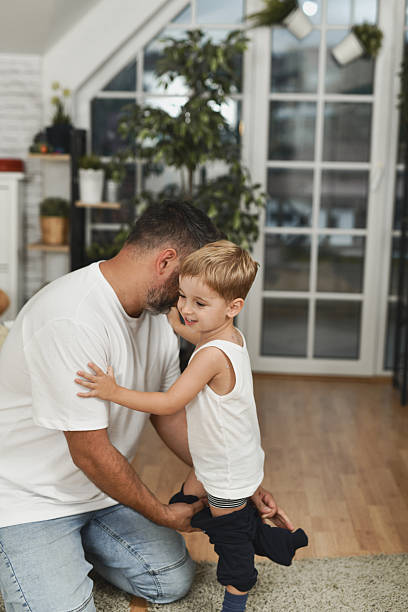 istock Father Helps Son Put On Pants At Home During Gentle Indoor Moment 2240257132