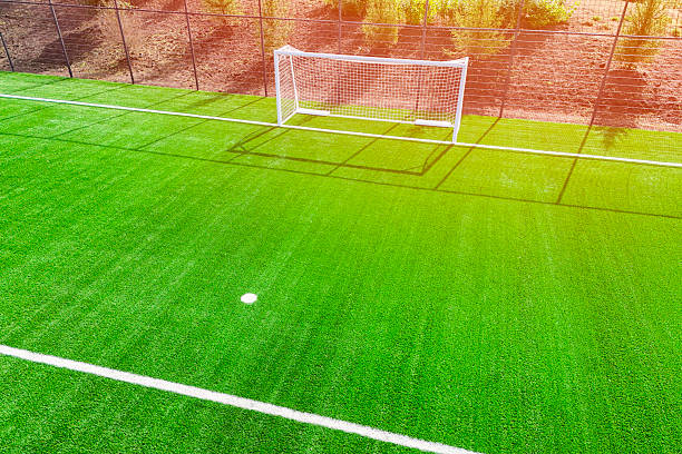 Soccer field with two separated goalposts, surrounded by lush greenery under a clear sky. The field appears unused, offering a serene and peaceful outdoor setting. High quality photo