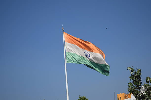 istock India flag flying high at Connaught Place with pride with plain white background, India flag fluttering, Indian Flag on Independence Day and Republic Day of India, tilt up shot, Har Ghar Tiranga 2240260033